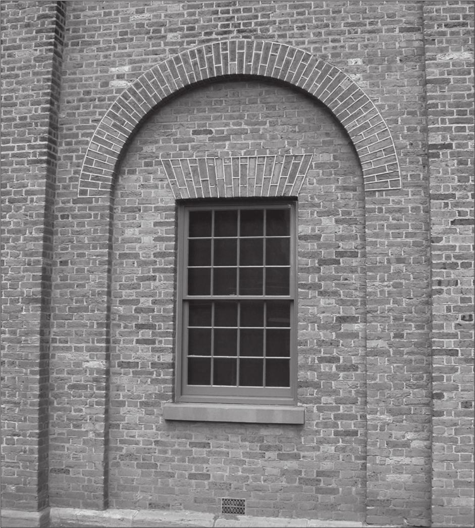 The window has two panes of glass that can slide up and the bricks around it make a semi-circular shape.