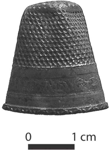 A black and white photograph of a slightly dented copper thimble.