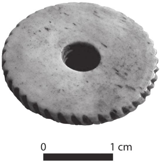 A black and white photograph of a circular lid with a hole in its centre.