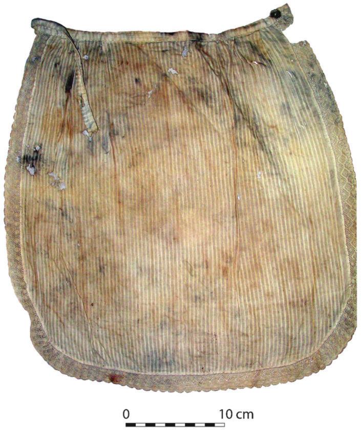 A photograph of a cotton apron with a lace trim and tie. The apron has stains over its striped pattern.